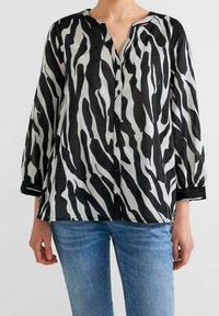 Camicia con stampa a zebre in bianco e nero, con scollatura a V, bottoncini davanti e maniche a tre quarti. Tessuto leggero e dalla texture con dettagli in pizzo.
