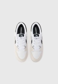 Hvide og beige sneakers med sorte detaljer, der har en glat læderoverdel, ruskinds-overlay og rund tå-design. Snøret med flade hvide snørebånd.