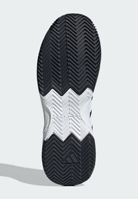 Podeszwa czarno-białego buta sportowego z wzorem bieżnika w jodełkę, gładką fakturą i charakterystycznym logo po bokach. Obecne elementy w kształcie zygzaka.