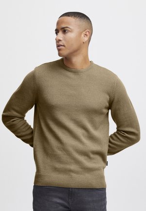 Suéter de punto verde oliva con cuello redondo, puños y dobladillo acanalados. La textura es suave, ofreciendo un ajuste casual.