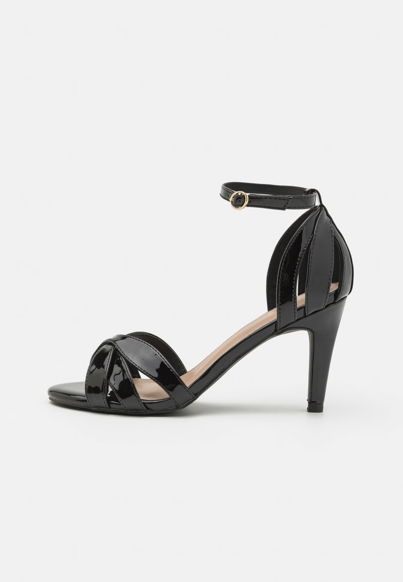 Μαύρες πατατούκες ψηλές με λουρί στον αστράγαλο, με σχέδιο διασταυρωμένων λουριών και ανοιχτή μύτη. Λεπτός ψηλός τακούνι και λεία υφή.