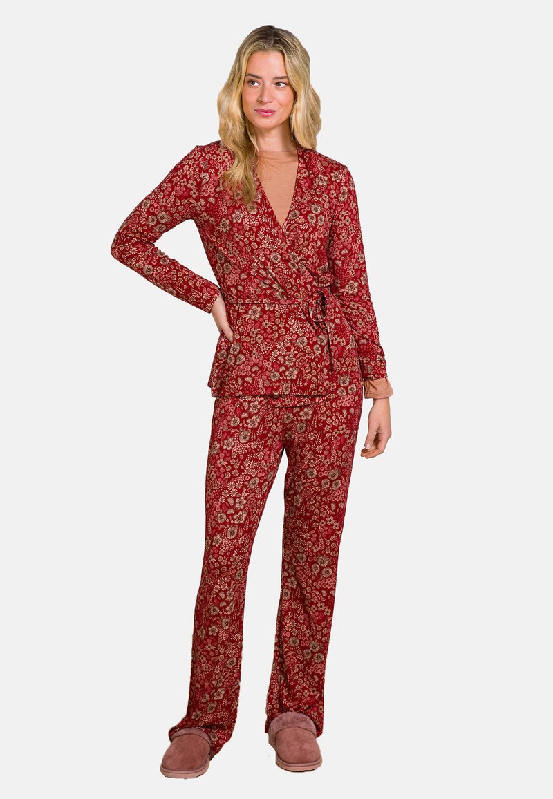 Roter Pyjama-Satz mit Blumenmuster, bestehend aus einem Wickeloberteil mit Bindegürtel und langen Ärmeln, kombiniert mit passenden geraden Hosen. Weicher Stoff.