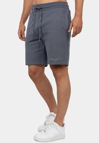 Grijze gebreide shorts met een elastische tailleband met trekkoord, zijzakken en een tonale geborduurde logo aan de zoom. Gestyled met witte sneakers.