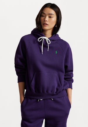 Purple hoodie made of soft fabric with a kangaroo pocket, white drawstrings, and a small green embroidered logo on the chest.