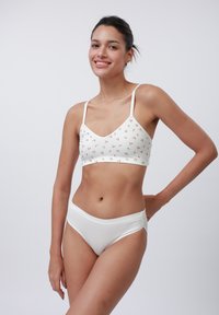 Vit bralette med liten blommig tryck och justerbara axelband, tillsammans med vita ribbade höga trosor. Slät textur genom hela.