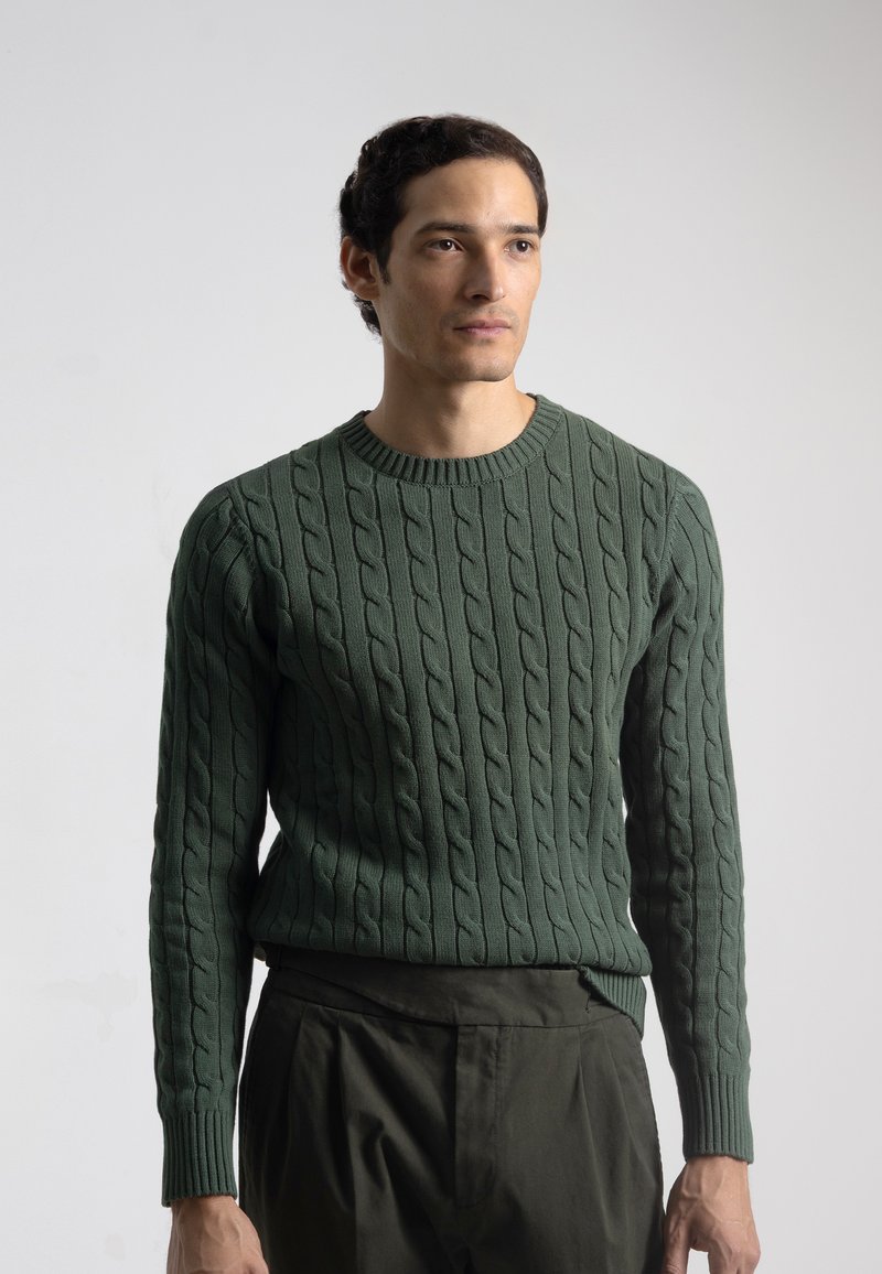 Suéter de punto trenzado verde oscuro con un escote redondo y mangas largas, que presenta patrones texturizados y puños de canalé. En general, tiene un diseño ajustado.