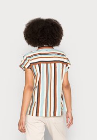 Chemise à manches courtes rayée en bleu clair, présentant des rayures verticales en brun, orange et jaune. Tissu léger avec une coupe décontractée.