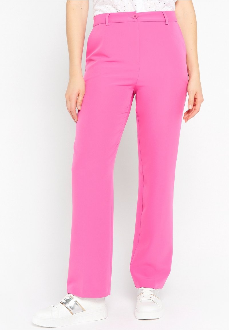 Pink, tailored pants with a smooth texture and wide-leg design, featuring a button closure, worn with white sneakers.