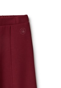 Burgundské tepláky s elastickým pasem, zdobené jemným potiskem loga a hladkým texturovaným materiálem. Navrženy pro pohodlí a snadné nošení.