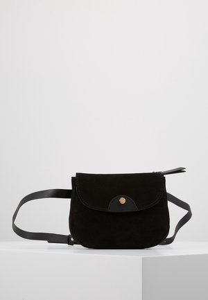 Sac banane en daim noir avec fermeture à rabat et petit bouton doré, présenté sur une surface blanche sur un fond gris clair.