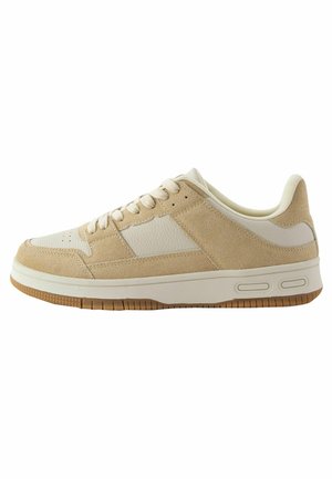 Beige Sneaker mit Obermaterial aus Wildleder und Leder, runde Zehenpartie, Schnürdesign, sichtbare Luftpolsterung und Außensohle aus Gummirubber.