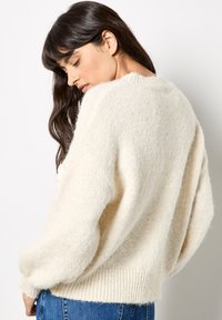 Maglione di color crema in maglia con una vestibilità comoda, caratterizzato da un tessuto morbido e texturizzato e polsini e orlo a costine.
