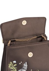 Sac à main marron avec poignée en chaîne dorée, présentant un design brodé de loup et de fleurs. Fermeture rabat avec bouton-pression et doublure en tissu à l'intérieur.
