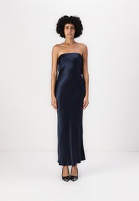 Ακατέργαστο ναυτικό σατέν μάξι φόρεμα με λεία, κομψή υφή. Φοριέται με μαύρες ψηλοτάκουνες γόβες. Απλός, στενός σχεδιασμός.