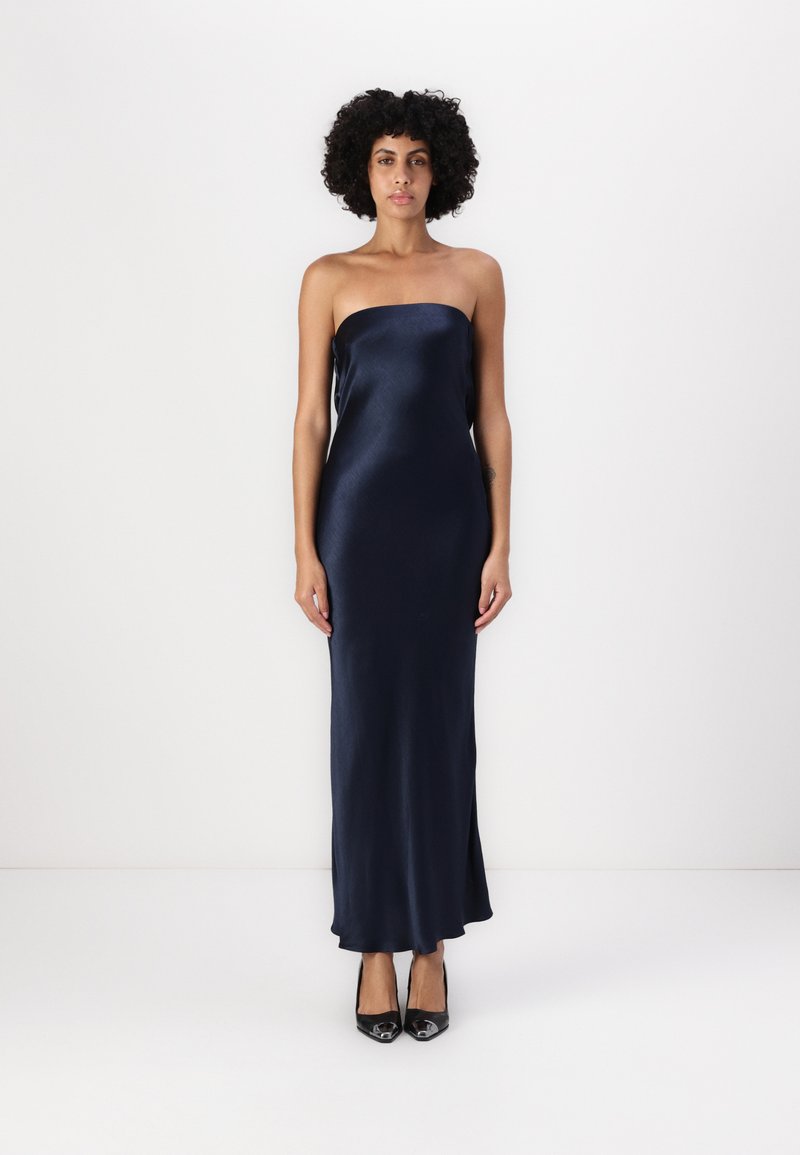 �Ακατέργαστο ναυτικό σατέν μάξι φόρεμα με λεία, κομψή υφή. Φοριέται με μαύρες ψηλοτάκουνες γόβες. Απλός, στενός σχεδιασμός.