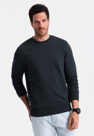 Dunkelblaues Sweatshirt aus weichem Material mit langen Ärmeln und gerippten Bündchen. Verfügt über einen runden Ausschnitt und ein kleines Logo am Saum.
