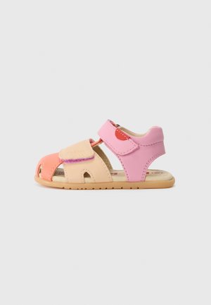Lille børnesandal i pink, fersken og beige med åben tå, justerbare stropper og blød sål på hvid baggrund.