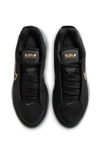 Ζευγάρι μαύρα αθλητικά παπούτσια με χρυσό σήμα Nike Swoosh, ετικέτα "Witness" στη γλώσσα και μικρά ασημένια λογότυπα Nike στο mesh του δακτύλου.