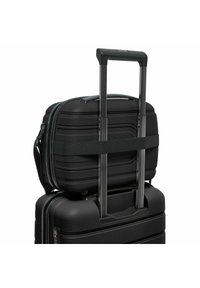 Zwarte harde koffer met een uitschuifbare handgreep en een kleinere tas bevestigd met een riem, met een gladde textuur en een patroonaccenten.