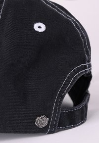 Căciulă neagră din bumbac cu cusături albe, având un accent de broderie circular și un logo de trandafir argintiu pe cureaua ajustabilă.