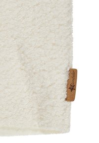 Close-up of soft, curly white fabric with a brown rectangular tag labeled "Sterntaler" attached on the right edge.
