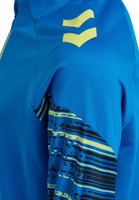 Blauses Sportshirt mit glatter Textur, gelben Akzenten und einem gemusterten Design in Blau-, Schwarz- und Gelbtönen auf dem Ärmel.