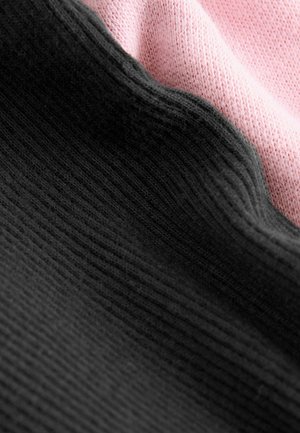 Black and pink knitted fabric layered, showing texture and stitching patterns; the two colors fold gently together, creating a soft appearance.