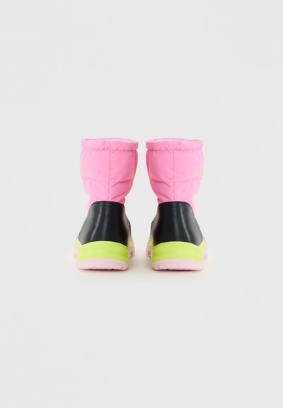 Par de botas de inverno cor-de-rosa com painéis de calcanhar pretos e solas intermédias amarelo neon, vistas pela parte de trás sobre um fundo branco.