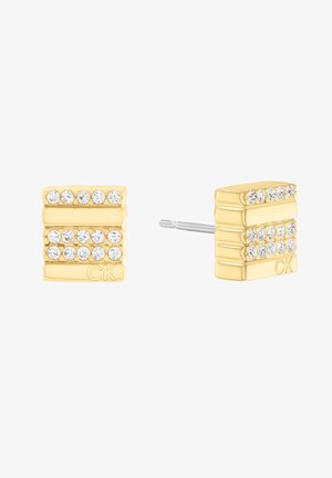 Boucles d'oreilles en métal doré avec trois rangées de cristaux transparents, au design rectangulaire et avec fermoir à tige. Le logo CK est présent d'un côté.