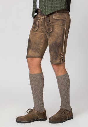 Traditionelle braune Lederhosen für Herren mit Stickerei, graue gestrickte Kniestrümpfe, braune Schnürschuhe und eine grüne Weste.