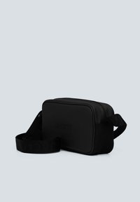 Černá obdélníková taška vyrobená z hladkého materiálu, s uzávěrem na zip, měkkým popruhem a vyraženým logem značky. Kompaktní design.