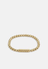 Pulsera elástica en tono dorado que presenta cuentas esféricas lisas y un acento rectangular plano y grabado con el nombre de la marca.