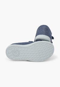 Modré džínové slip-on boty s bílou gumovou podrážkou. Zaoblená špička, strukturované švy a detail s etiketou na boku.
