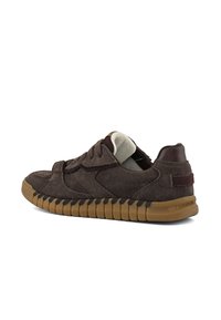 Zapatillas de ante marrón con punta redonda, parte superior texturada y suela de goma. Presentan acentos contrastantes y un collar acolchado.