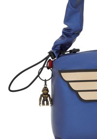 Borsa a tracolla sintetica blu con texture lucida, caratterizzata da un design con ali color crema, contorni neri e un ciondolo di una scimmia bronzo attaccato.