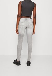 Grå skinny jeans med en slät, blekt finish, med två bakfickor med böjd sömnad. I kombination med svarta skor.