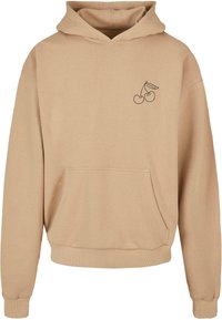 Beige bomull hettegenser med en frontlomme, snorhette og svart kirsebærgrafikk på venstre bryst. Ribbestrikkede mansjetter og hem.