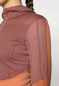 Langärmliges Oberteil in verschiedenen Brauntönen mit Kapuze, aus strukturiertem Stoff und im Color-Block-Design, mit Logo-Detail am Ärmel.