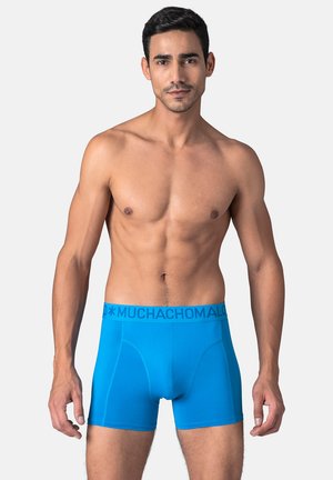 Blå boxer shorts med en glat tekstur, elastisk linning med "MUCHACHOMALO"-mærkning og en tætsiddende design, der viser minimale sømme.