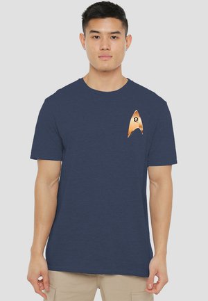 Dunkelblaues Kurzarm-T-Shirt aus weichem Stoff, mit einem kupferfarbenen Emblem auf der linken Brust, das eine stilisierte Pfeilform darstellt.