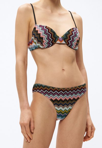 Σετ μπικίνι με πολύχρωμο ζιγκ-ζαγκ μοτίβο και μαύρες λεπτομέρειες, κατασκευασμένο από υφασμάτινη υφή. Το τοπ διαθέτει ενισχυμένα κύπελλα και λεπτές τιράντες.