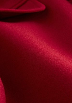 Roter Wollstoff, strukturierte Oberfläche mit glatter Haptik, mit einem gefalteten Rand und subtiler Glanz. Gleichmäßige Farbe, ohne Muster oder Akzente.