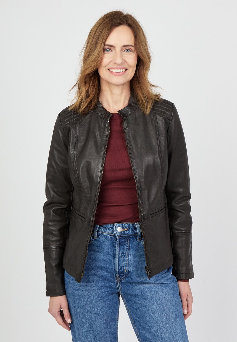 Sort læderjakke med lynlås, rund krave og vertikale syninger. Båret med en maroon top og højtaljede blå jeans.