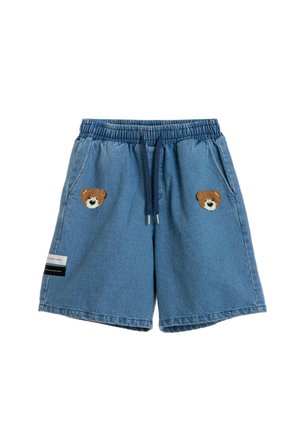 Pantalones cortos vaqueros con cintura elástica, cordón azul marino, dos bolsillos delanteros, parches con la cara de un osito de peluche en cada lado y una pequeña etiqueta en la pierna izquierda.