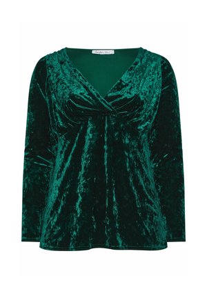 Top de terciopelo en verde profundo con mangas largas, escote en forma de V y detalles recogidos en el busto, que presenta una textura suave y reflectante.