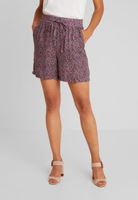 Shorts floraux violets avec une taille à cordon, des poches latérales et une coupe ample, présentant un petit motif floral détaillé sur l'ensemble.