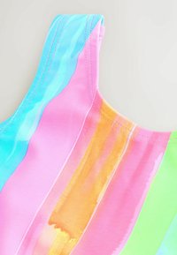 Bañador multicolor con rayas verticales en azul, rosa, naranja y verde. El material es suave con detalles de costura visibles.