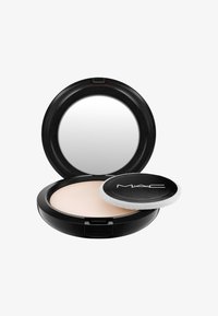 Polvere compatta MAC con astuccio nero tondo, specchio interno e applicatore a spugna su una polvere beige chiaro. Texture liscia visibile.