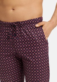 Marineblauwe sweatpants met een geometrisch ruitpatroon in rood en wit, zachte textuur en zijzakken voor extra functionaliteit.
