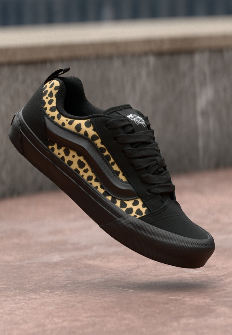 Svart sneakers med leopardmønsterdetaljer, med en strukturert overdel, rund tå, flat svart såle og polstret krage. Snøring design.